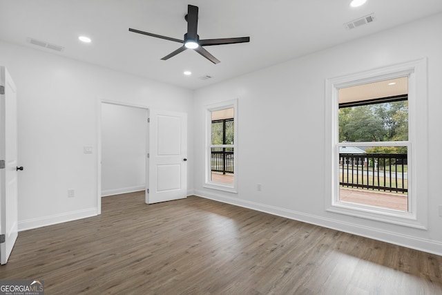 empty room featuring ceiling fan, a wealth of natural light, and dark hardwood / wood-style floors