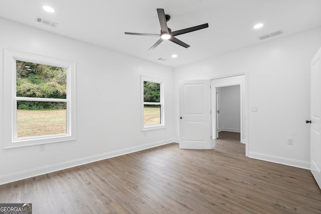 empty room featuring dark hardwood / wood-style flooring, ceiling fan, and a healthy amount of sunlight