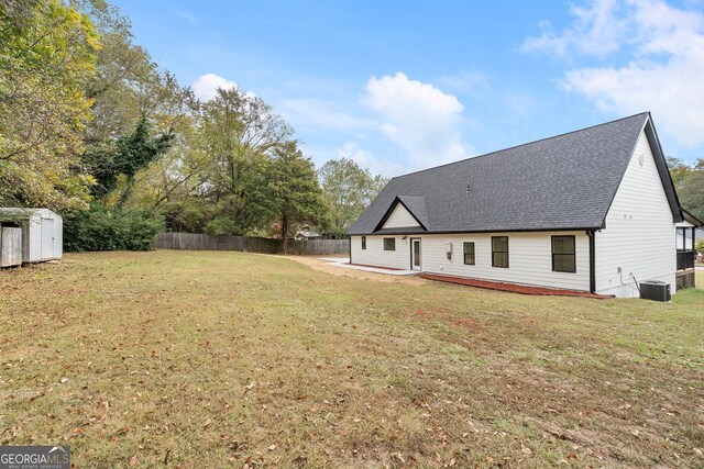 rear view of house featuring a lawn and central AC