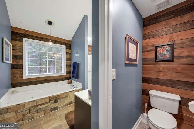 bathroom with toilet, wood walls, and tiled tub