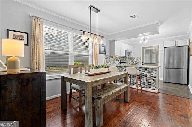 dining area with dark hardwood / wood-style floors, an inviting chandelier, and crown molding