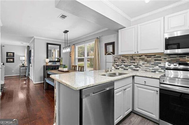 kitchen with white cabinets, stainless steel appliances, ornamental molding, and light stone counters