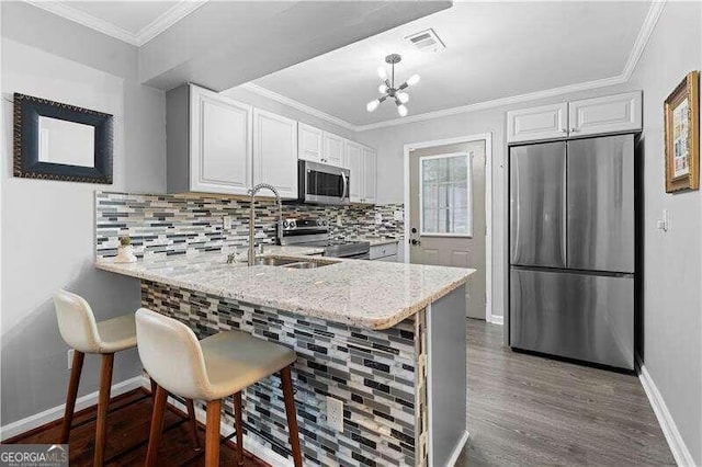 kitchen featuring a kitchen bar, kitchen peninsula, appliances with stainless steel finishes, and white cabinetry