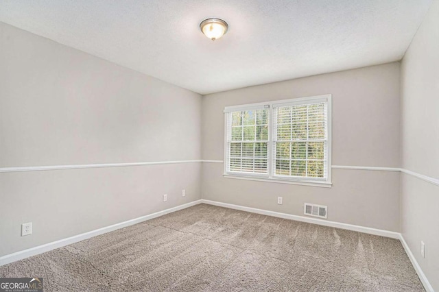 carpeted empty room featuring a textured ceiling