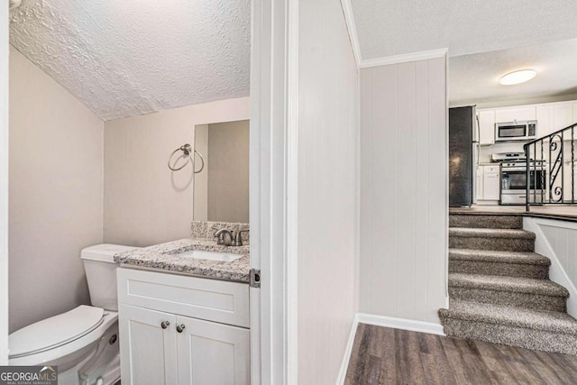 bathroom with hardwood / wood-style floors, a textured ceiling, toilet, and vanity