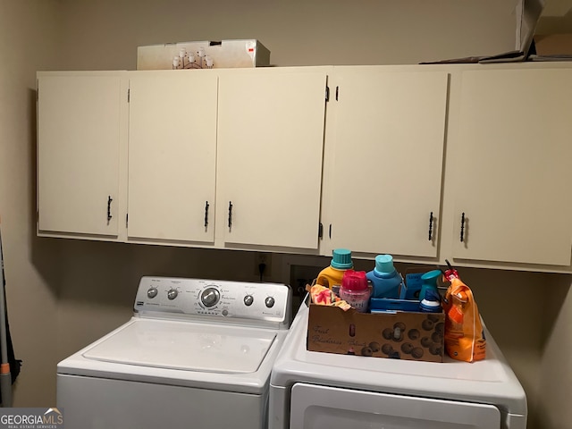 clothes washing area with separate washer and dryer and cabinets