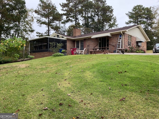 rear view of house with a sunroom and a lawn