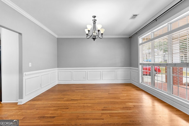 unfurnished room featuring a chandelier, light hardwood / wood-style floors, and ornamental molding