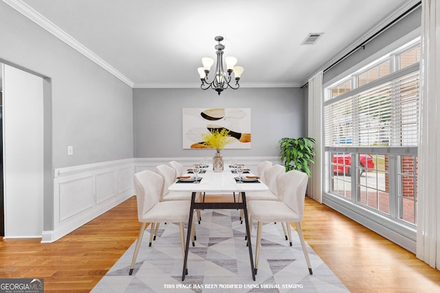 dining space with a wealth of natural light, crown molding, and light hardwood / wood-style floors