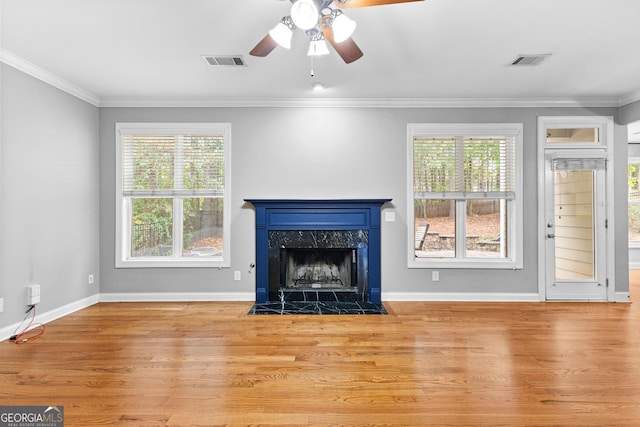 unfurnished living room featuring light hardwood / wood-style floors, plenty of natural light, ornamental molding, and a premium fireplace