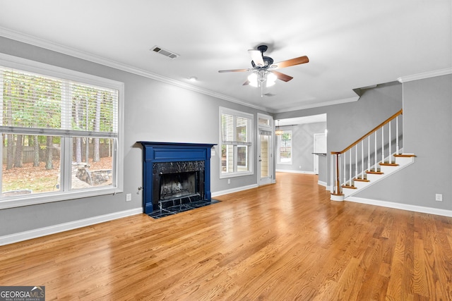 unfurnished living room featuring plenty of natural light, ornamental molding, a high end fireplace, and light hardwood / wood-style flooring