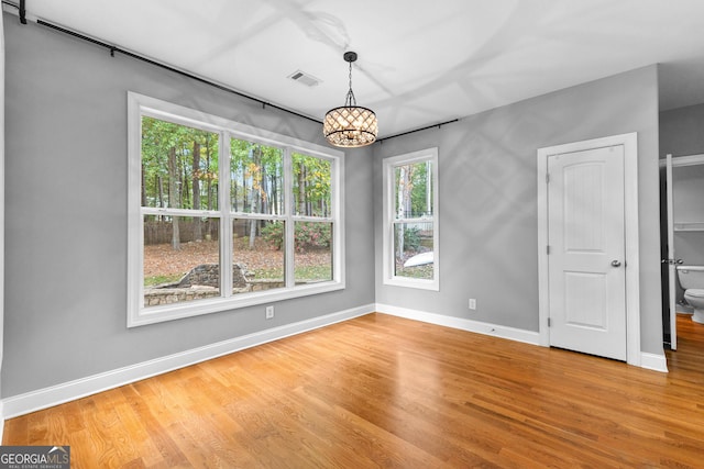 spare room featuring hardwood / wood-style floors and an inviting chandelier