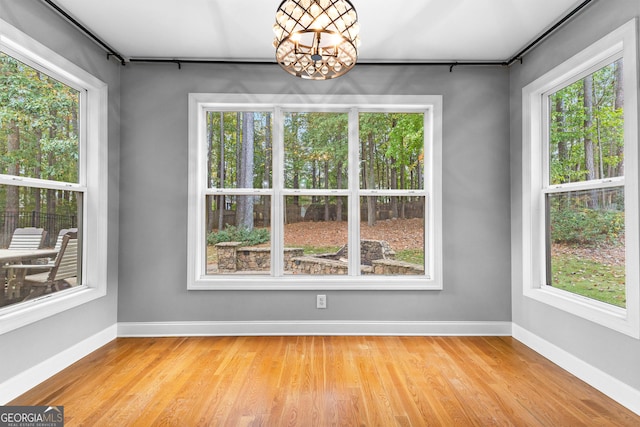 unfurnished dining area featuring light hardwood / wood-style floors, a healthy amount of sunlight, and an inviting chandelier