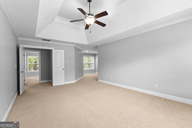 unfurnished room featuring a raised ceiling, ceiling fan, light carpet, and ornamental molding