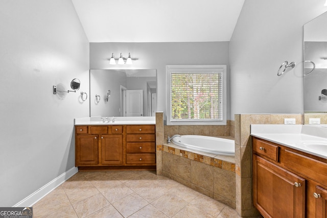 bathroom with tile patterned floors, vanity, a relaxing tiled tub, and vaulted ceiling