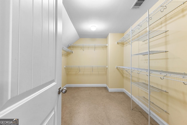 spacious closet featuring light colored carpet and lofted ceiling