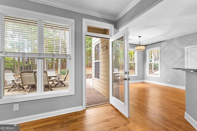 doorway to outside featuring a wealth of natural light, french doors, ornamental molding, and light wood-type flooring