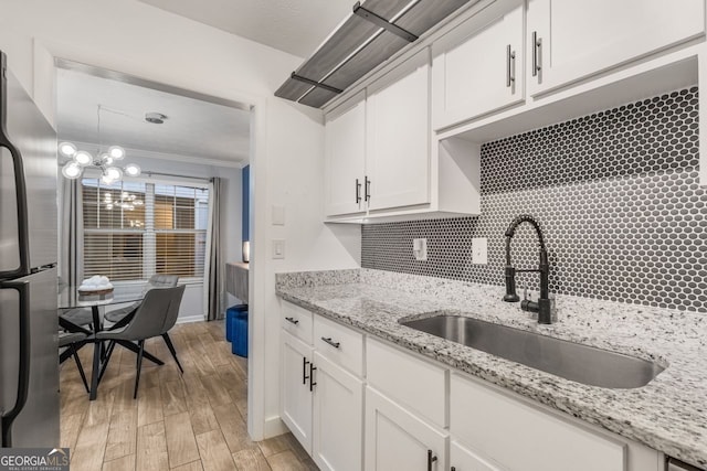 kitchen with sink, ornamental molding, light hardwood / wood-style floors, white cabinetry, and stainless steel refrigerator