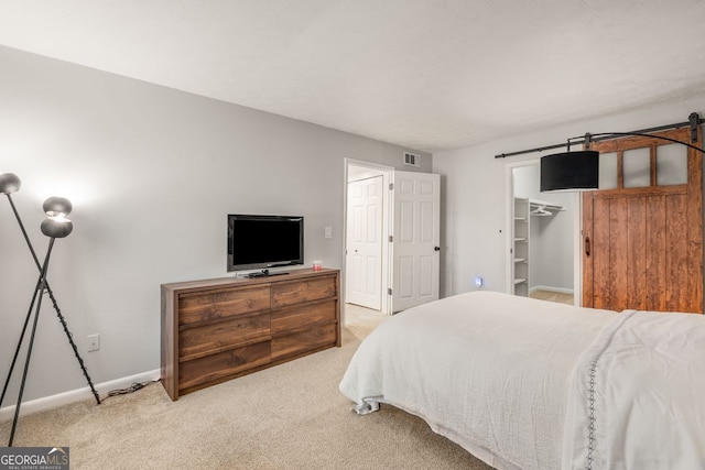 carpeted bedroom featuring a walk in closet and a closet