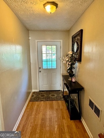 doorway to outside featuring hardwood / wood-style floors and a textured ceiling