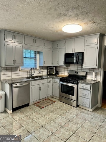 kitchen with stainless steel appliances, decorative backsplash, a textured ceiling, sink, and light tile patterned floors