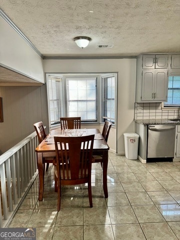 dining area featuring ornamental molding, a textured ceiling, light tile patterned floors, wooden walls, and sink