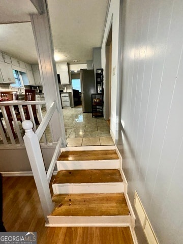 stairway with wood walls and hardwood / wood-style flooring