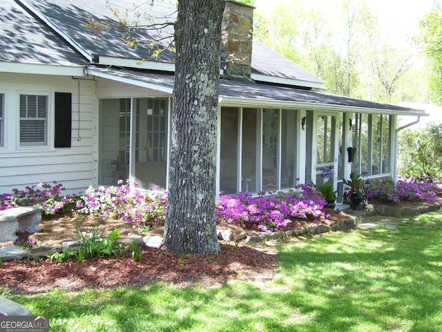 view of property exterior featuring a sunroom and a yard