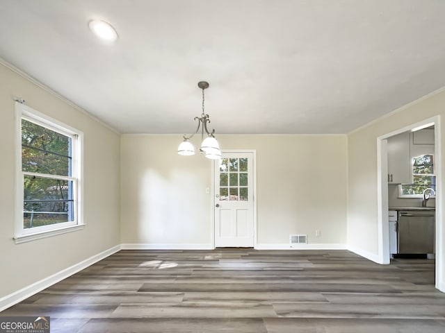 unfurnished dining area featuring ornamental molding, sink, a notable chandelier, and dark hardwood / wood-style floors