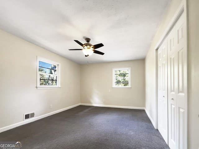 unfurnished bedroom featuring a closet, ceiling fan, and dark carpet