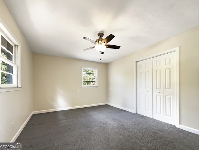 unfurnished bedroom featuring a closet, dark colored carpet, and ceiling fan