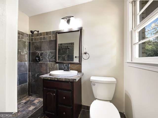 bathroom with vanity, toilet, and tiled shower