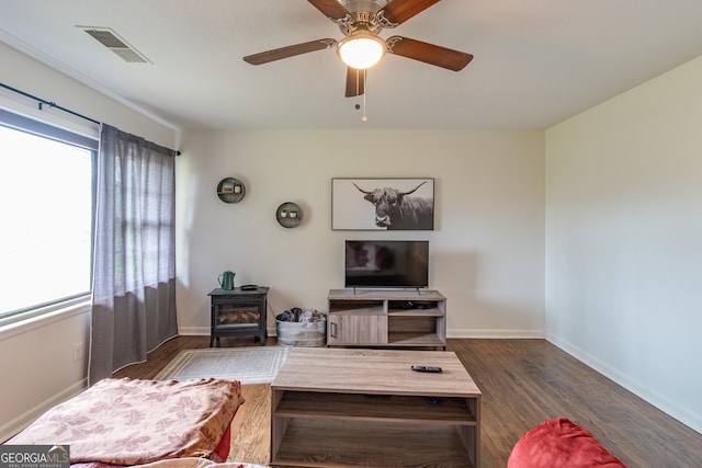 living room with a wood stove, dark hardwood / wood-style floors, and ceiling fan