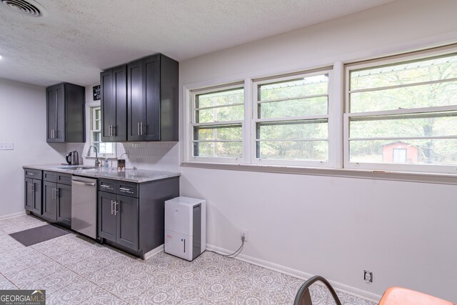 kitchen featuring light stone counters, a textured ceiling, decorative backsplash, sink, and stainless steel dishwasher