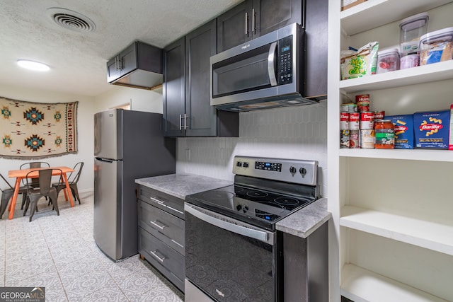 kitchen with backsplash, appliances with stainless steel finishes, a textured ceiling, and light tile patterned flooring