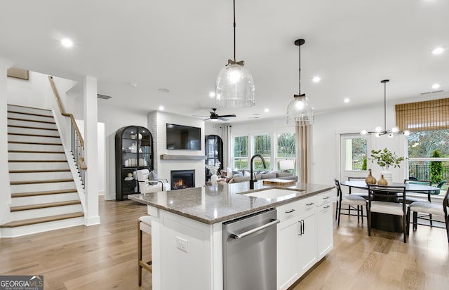 kitchen with a center island with sink, sink, white cabinetry, hanging light fixtures, and dishwasher