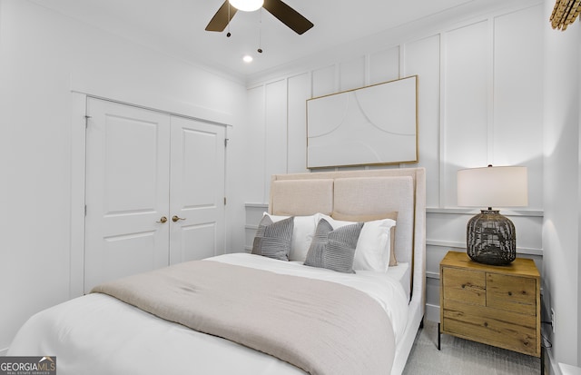 bedroom with ceiling fan, light carpet, and a closet