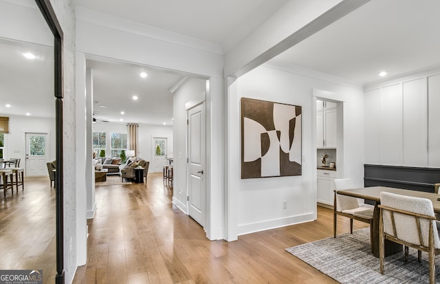 corridor with light hardwood / wood-style floors and crown molding