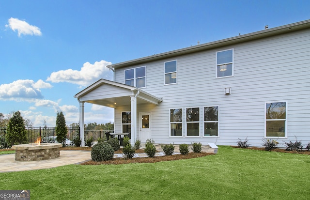 rear view of property featuring a lawn and an outdoor fire pit