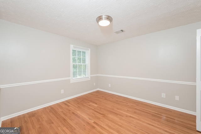 empty room with a textured ceiling and hardwood / wood-style flooring