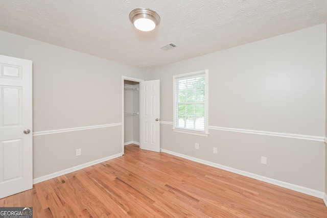 unfurnished bedroom with a textured ceiling and light hardwood / wood-style floors