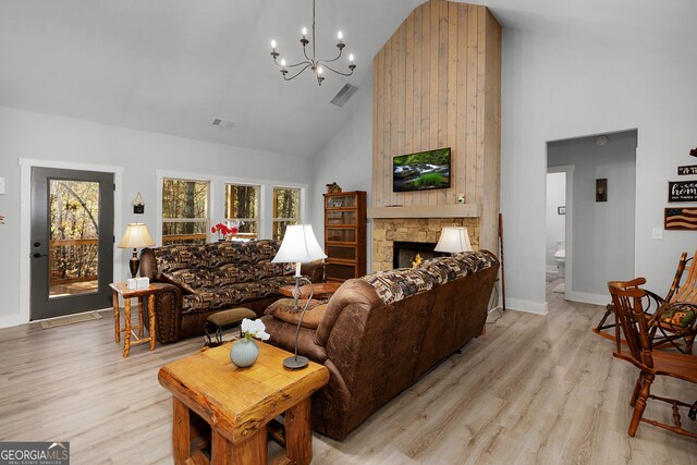 living room featuring an inviting chandelier, a fireplace, high vaulted ceiling, and light hardwood / wood-style flooring