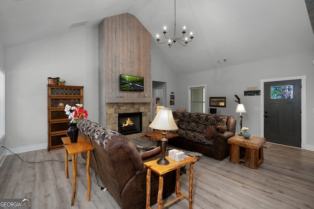 living room with a fireplace, high vaulted ceiling, a notable chandelier, and light hardwood / wood-style flooring