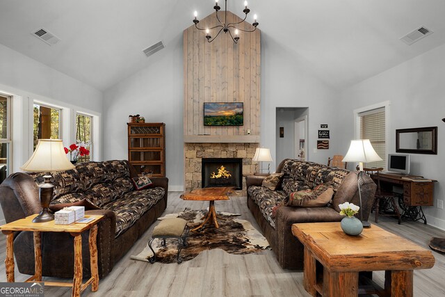 living room with a fireplace, high vaulted ceiling, light hardwood / wood-style flooring, and a chandelier