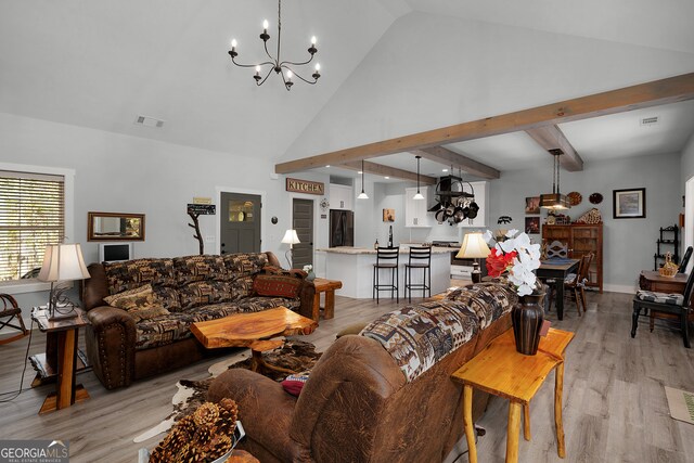 living room with an inviting chandelier, high vaulted ceiling, and light hardwood / wood-style flooring