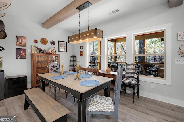 dining area featuring beamed ceiling and hardwood / wood-style flooring