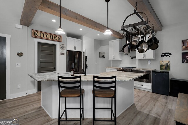 kitchen with a kitchen island, beam ceiling, light stone counters, white cabinetry, and stainless steel appliances