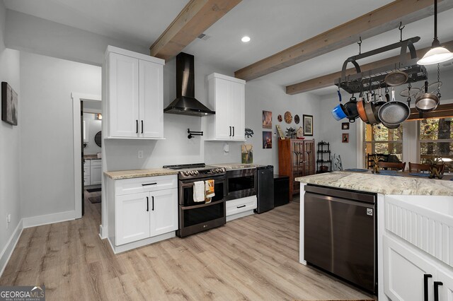 kitchen featuring beamed ceiling, white cabinetry, wall chimney range hood, and appliances with stainless steel finishes