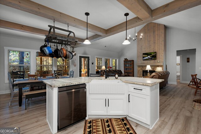 kitchen featuring white cabinets, decorative light fixtures, a stone fireplace, and a kitchen island with sink