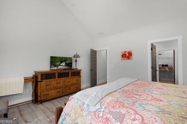 bedroom with light hardwood / wood-style floors and high vaulted ceiling